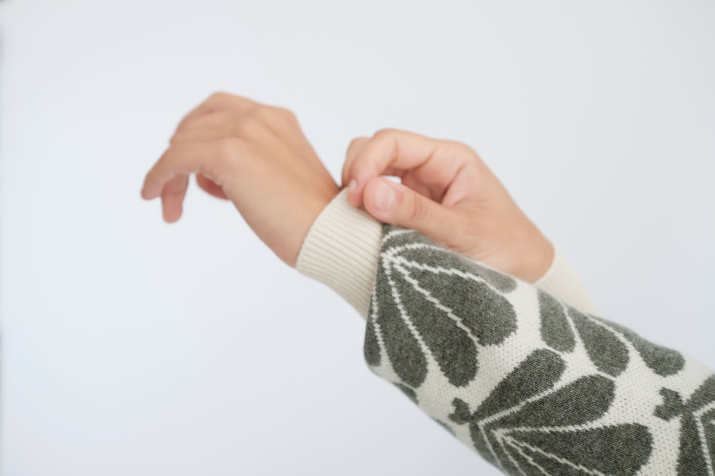 Detalj av erme på genser med kamskjell-motiv.